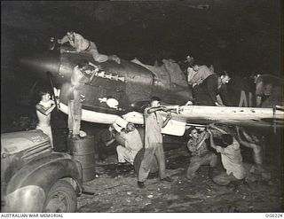 VIVIGANI, GOODENOUGH ISLAND, PAPUA. 1943-11-02. GROUND STAFF WORKING BY THE LIGHT OF TRUCK HEADLAMPS TO PREPARE A KITTYHAWK AIRCRAFT OF NO. 77 SQUADRON RAAF FOR A DAWN STRIKE