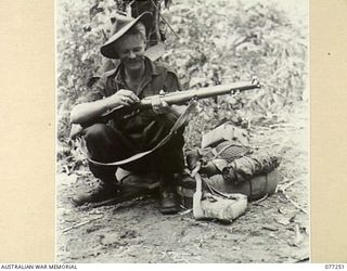 DOYABIE AREA, BOUGAINVILLE ISLAND. 1944-11-23. QX34395 SERGEANT A. M. MITCHELL, 9TH INFANTRY BATTALION DRYING HIS RIFLE AFTER FORDING THE LARUMA RIVER ON THE NUMA NUMA TRAIL AS THE UNIT MOVES ..