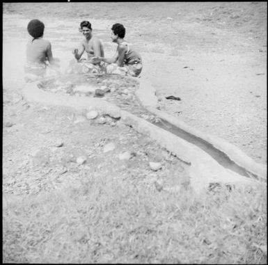 Man and two women sitting near a hot springs pool, Fiji, 1966 / Michael Terry