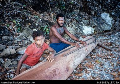 Daniel and Relative: Daniel, Company field assistant at Mwatu Camp, with hull of unfinished canoe and a fishing spear