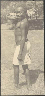 Member of Government House staff holding a bowl of fruit on his shoulder, Rabaul, New Guinea, ca. 1929 / Sarah Chinnery