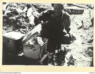 TSIMBA RIDGE, BOUGAINVILLE ISLAND. 1945-02-06. SX38081 PRIVATE A.F. (COOKIE) FERGUSSON, COOKING A MEAL FOR THE TROOPS OF THE 101ST BRIGADE SUPPORT COMPANY