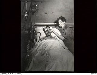 Lae, New Guinea. 1944-08-02. Sister Winifred Quin adjusting the tubing attached to a patient suffering from peritonitis at the 2/7th Australian General Hospital