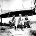 Three soldiers sitting under makeshift tent after Battle of Guadalcanal, 1942
