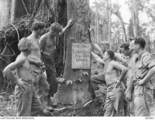 MIVO RIVER, BOUGAINVILLE, 1945-08-29. TROOPS OF 15 INFANTRY BATTALION LOOKING AT THE SIGN THEY ERECTED ON THE BUIN ROAD FOR THE BENEFIT OF SIGHTSEERS VISITING THE AREA