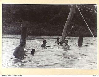 AITAPE AREA, NEW GUINEA, 1944-11. TROOPS OF 22 FIELD COMPANY, ROYAL AUSTRALIAN ENGINEERS, USE WATER PRESSURE TO DRIVE PILES IN THE CONSTRUCTION OF A BRIDGE LOCATED APPROXIMATELY HALF WAY BETWEEN ..