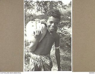 KONEKARU, PAPUA. 1943-12-02. VIROBO, A YOUNG PAPUAN BOY, CARRYING THREE DAYS RATIONS ON HIS SHOULDER