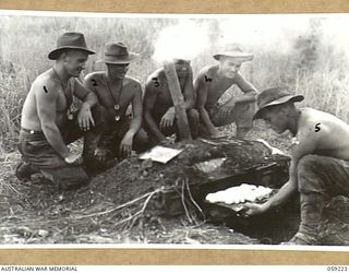 KUMBARUM, NEW GUINEA, 1943-10-23. THE COOK OF "F" TROOP, 54TH BATTERY, 2/4TH AUSTRALIAN FIELD REGIMENT COOKING A BATCH OF SCONES IN HIS IMPROVISED OVEN MADE OF METAL AMMUNITION BOXES AND BANKED ..