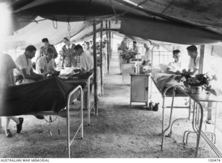 PORT MORESBY, NEW GUINEA, 1944-05-29. MAJ M.B. DUNCAN (3) MEDICAL OFFICER, AND LANCE CORPORAL COOMBES, AUSTRALIAN ARMY MEDICAL WOMEN'S SERVICE (AAMWS) (7) TREATING PATIENTS IN WARD 10, 2/1ST ..