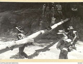 FARIA RIVER, NEW GUINEA. 1944-01-20. MEMBERS OF THE 2/5TH FIELD AMBULANCE AND ARTILLERY UNITS CROSSING THE FARIA RIVER ON THEIR WAY TO THE FRONT LINE