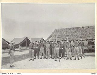 CAPE WOM, WEWAK AREA, NEW GUINEA. 1945-10-13. HEADQUARTERS C COMPANY, 2/1 GUARD REGIMENT, ON PARADE. CAPTAIN H.W. QUILTY, OFFICER COMMANDING, IS ADDRESSING THE MEN