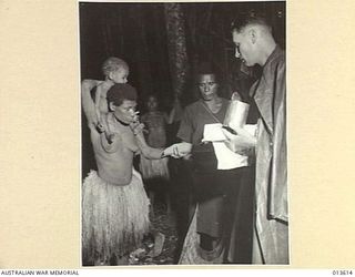 1942-11-19. NEW GUINEA. KOKODA. AN AUSTRALIAN OFFICER IN CHARGE OF THE NATIVES BUY FRUIT FROM NATIVES IN A VILLAGE THAT HAS JUST BEEN TAKEN FROM THE JAPANESE. PAYMENT IS ALSO MADE IN TRADE TOBACCO. ..