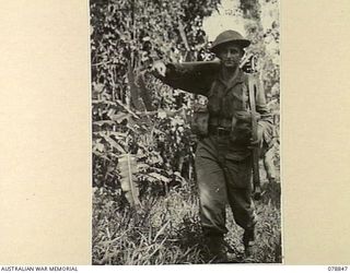 BOUGAINVILLE ISLAND. 1945-01-31. Q100119 PRIVATE A.E. IRONS, "D" COMPANY, 9TH INFANTRY BATTALION, UNSHAVEN AND COVERED WITH MUD AS HE RETURNS TO THE UNIT CAMP ON THE MOSIGETTA ROAD AFTER SPENDING ..