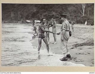 BUT-DAGUA AREA, NEW GUINEA. 1945-04-12. LIEUTENANT GENERAL J. NORTHCOTT, CHIEF OF THE GENERAL STAFF (2), RECEIVES HIS SWAGGER CANE FROM PRIVATE W. RICHARDSON (1), DURING HIS VISIT WITH SENATOR J.M. ..