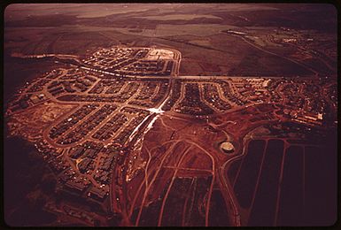 "NEW TOWN" GROWS WHERE PINEAPPLES USED TO THRIVE. PINEAPPLE GROWERS ARE DEVELOPING THEIR OWN "SURPLUS LAND." THIRTEEN HUNDRED ACRES OF A PROJECTED THIRTY-FIVE HUNDRED ACRE DEVELOPMENT HAVE BEEN REZONED SINCE THE START IN 1958