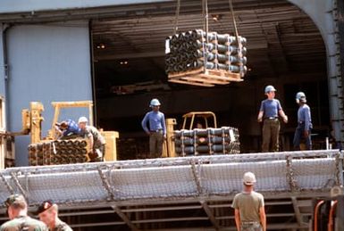 Pallets of ordnance are loaded aboard the amphibious assault ship USS GUAM (LPH-9) for deployment to Saudi Arabia in support of Operation Desert Shield