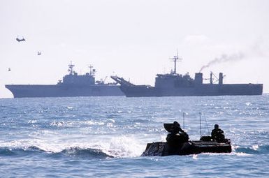 Marines from the 1ST Plt., Co. D, 2nd Assault Amphibious Bn., Camp Lejeune, North Carolina, bring troops ashore on LVTP-7 tracked landing vehicles during Exercise Crisex '81. The amphibious assault ship USS SAIPAN (LHA-2) and tank landing ship USS BARNSTABLE COUNTY (LST-1197) are visible in the background