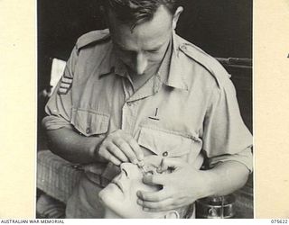 MARKHAM VALLEY, NEW GUINEA. 1944-08-28. VX89687 SERGEANT A. DUKE, MEDICAL ORDERLY, ATTENDING TO A PATIENT IN THE REGIMENTAL AID POST OF THE 4TH FIELD REGIMENT