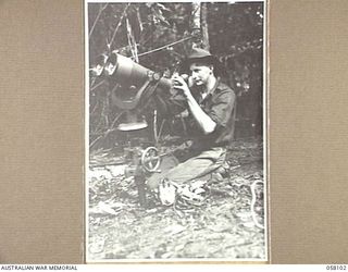 FINSCHHAFEN, NEW GUINEA, 1943-10-02. NX39663 PRIVATE J.F. SMITH, 9TH AUSTRALIAN DIVISION, EXAMINES A HUGE PAIR OF JAPANESE BINOCULARS WHICH WERE CAPTURED BY AN AIF BATTALION DURING THE CAMPAIGN