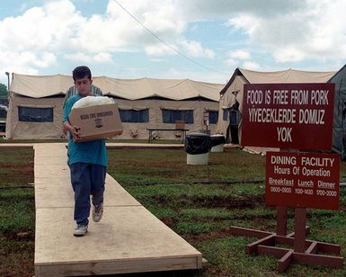 Kurdish refugees carries food supplies from the dining facility back to their temporary home at Anderson Air Force Base, Guam. OPERATION PACIVIC HAVEN provides airlift for some 2,700 refugees fleeing Iraq. The refugees will be housed at Anderson AFB, Guam, while they go through the immigration process for residence into the United States