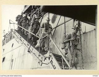 HOSKINS, NEW BRITAIN. 1944-10-08. TROOPS OF THE 36TH INFANTRY BATTALION COMING DOWN THE GANGWAY OF THE DUTCH TROOPSHIP "SWARTENHONDT" TO ENTER THE BARGES FOR TRANSPORT TO THE BEACH