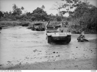 MILNE BAY, PAPUA. 1942-10. THE MAIN ROAD THROUGH THE AREA OCCUPIED BY AUSTRALIAN TROOPS IN THE GILI GILI DISTRICT CROSSES SEVERAL CREEKS. THIS PICTURE SHOWS A MOTOR VEHICLE CONVOY NEGOTIATING ONE ..