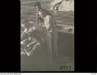 PORT MORESBY, PAPUA. C. 1944. A CASUALTY IN A STOKES LITTER LIFTED ON BOARD A MOTOR LAUNCH OF THE RAAF RESCUE SERVICE WITH THE HELP OF TWO PAPUAN NATIVE CREW MEMBERS