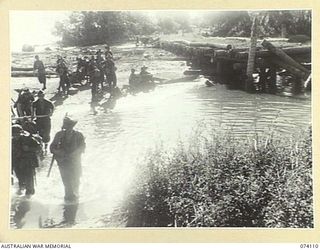 HANSA BAY, NEW GUINEA. 1944-06-16. TROOPS OF THE 4TH INFANTRY BRIGADE CROSSING THE SAKULA RIVER. THE WRECKED BRIDGE WAS BLOWN UP BY THE RETREATING JAPANESE