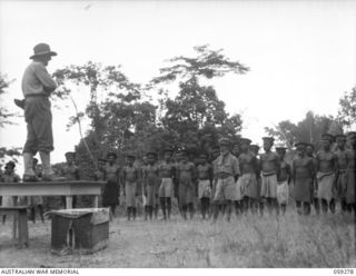 HOPOI, NEW GUINEA, 1943-10-30. NX155085 CAPTAIN R.G. ORMSBY OF THE AUSTRALIAN AND NEW GUINEA ADMINISTRATIVE UNIT ADDRESSING A CONFERENCE OF THE CHIEFS OF THE VILLAGES IN THE AREA. ALSO SEEN IS ..