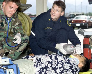 Straight on medium close-up shot as US Air Force SENIOR MASTER Sergeant Tim Bosch (Right), Deputy Fire CHIEF, Hickam Air Force Base, Hawaii, demonstrates emergency medical technician skills with the help of medical technician,SENIOR AIRMAN Joseph Marsilio. SMSGT Bosch was selected as one of the United States Air Force 12 Oustanding Airmen for 1999