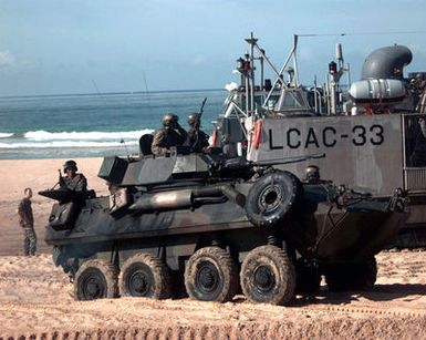 US Marines on the ground and in a light armored vehicle prepare to off load equipment from a Landing Craft Air Cushion (LCAC) during a beach assault at Pacific Missile Range Facility, Barking Sands, Kauai, Hawaii, during RIMPAC '96