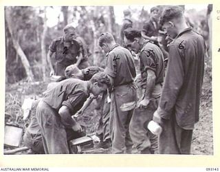 WEWAK AREA, NEW GUINEA, 1945-06-17. PTE J.E. DELANEY, A COOK (1), ISSUING FRITTERS TO MEN OF B COMPANY, 2/8 INFANTRY BATTALION BACK FROM PATROL. B COMPANY IS LOCATED IN SUCH A POSITION THAT IT IS ..
