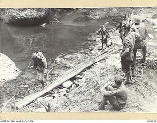 PAPUA, NEW GUINEA. 1942-10. NATIVE CARRIERS CROSSING GOLDIE RIVER ON WAY TO NAURO RIDGE. MANY JAPANESE WERE KILLED IN THIS GORGE