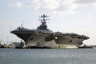 US Navy (USN) Sailors aboard the USN Nimitz Class Aircraft Carrier USS ABRAHAM LINCOLN (CVN 72) man the rails as their ship, escorted by tugboats, pulls into port for a scheduled visit at Naval Station (NS) Pearl Harbor, Hawaii (HI). The LINCOLN is participating in Exercise Rim of the Pacific (RIMPAC) 2006, an exercise designed to increase the tactical proficiency of participating units in a wide array of combined sea operations. RIMPAC 2006 brings together military forces from Australia (AUS), Canada (CAN), Chile (CHL), Peru (PER), Japan (JPN), the Republic of Korea (KOR), United Kingdom (UK) and the United States (US)