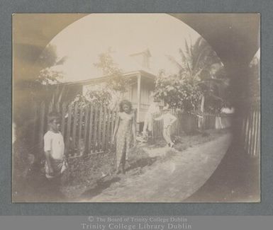 Photograph of a Samoan child, young woman, and two men posing outside a house in Apia, Samoa