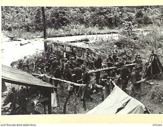 FARIA VALLEY, NEW GUINEA, 1944-02-09. PERSONNEL OF THE 2/10TH INFANTRY BATTALION MAKE A BUSY SCENE AT THE SALVATION ARMY HUT ARE IRIE, MAIN STREAM, ON THE UPPER REACHES OF THE FARIA RIVER. THEY ARE ..