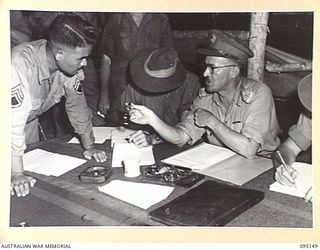 TOKO, BOUGAINVILLE, 1945-08-18. BRIGADIER A.R. GARRETT, BRIGADIER, GENERAL STAFF, HEADQUARTERS 2 CORPS, EXPLAINING TO AN INTERPRETER THE DIFFERENCE IN TIME OF 2 HOURS AND COMMANDING THE JAPANESE ..