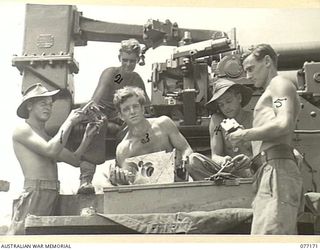 WUNUNG PLANTATION, JACQUINOT BAY, NEW BRITAIN. 1944-11-24. MEMBERS OF THE CREW OF NO. 2 GUN, 472ND HEAVY ANTI-AIRCRAFT TROOP, GAUGING AMMUNITION BESIDE THEIR 3.7" ANTI-AIRCRAFT GUN. IDENTIFIED ..