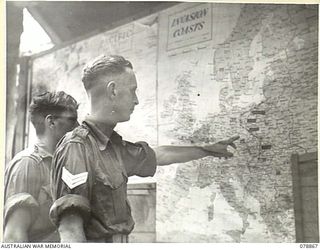 TOROKINA, BOUGAINVILLE ISLAND. 1945-02-04. Q130393 SIGNALLER H.F. SMITH (1) AND VX102544 SERGEANT A.W. ALEXANDER (2) STUDYING THE WALL MAPS OF THE EUROPEAN CAMPAIGN AT THE EDUCATION CENTRE OF THE ..
