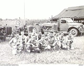 LAE, NEW GUINEA, 1945-12-24. MEMBERS OF 4 INDEPENDENT FARM COMPANY. MECHANICAL EQUIPMENT ON STRENGTH TO THE UNIT IS IN THE BACKGROUND. NOTE THE IMPROVISED TRACTOR ON THE EXTREME LEFT