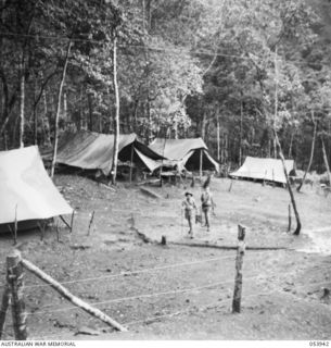 UBERI, NEW GUINEA. 1943-07-08. TEST POINT AND LINESMEN'S CAMP OF THE 18TH NEW GUINEA LINES OF COMMUNICATION, SIGNALS, AIF, ALONG THE KOKODA TRAIL. THE TWO SIGNALMEN ARE LEAVING THE CAMP TO REPAIR A ..