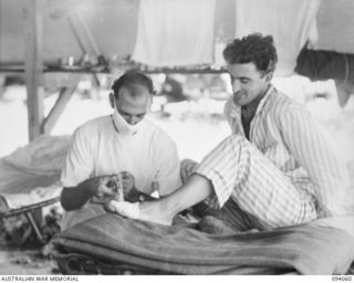 TOROKINA, BOUGAINVILLE, 1945-07-16. PTE B.M. HARKIN, MEDICAL ORDERLY, 106 CASUALTY CLEARING STATION (1), DRESSING THE WOUND OF PTE A.J. BASSETT, 8 INFANTRY BATTALION (2)