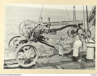 HOSKINS, NEW BRITAIN. 1944-10-09. A ROADGRADER OF THE AUSTRALIAN ARMY ENGINEERS BEING SWUNG ASHORE BY ONE OF THE CRANES OF THE DUTCH TROOPSHIP "SWARTENHONDT" BY A MEMBER OF THE 2/31ST DOCKS ..