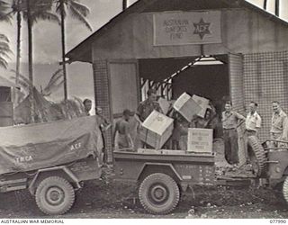 PALMALMAL PLANTATION, NEW BRITAIN. 1944-12-29. PERSONNEL OF THE AUSTRALIAN COMFORTS FUND UNIT, 5TH BASE SUB AREA LOADING CHRISTMAS HAMPERS ONTO A JEEP TRAILER FOR DELIVERY TO THE 4TH INFANTRY ..