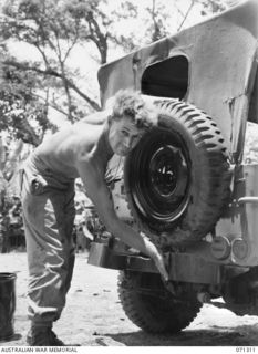 RAMU VALLEY, NEW GUINEA, 1944-03-21. QX16631 C.F. GOVES (1), OF HEADQUARTERS, 7TH DIVISION, AT WORK CLEANING HIS JEEP