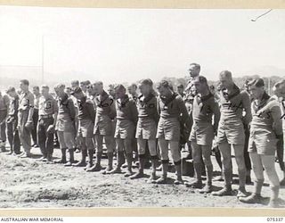LAE, NEW GUINEA. 1944-08-13. FOOTBALLERS STAND WITH HEADS BOWED IN PRAYER DURING THE OFFICIAL OPENING CEREMONY OF THE CORPORAL RONALD RILEY MEMORIAL RECREATION GROUND. IDENTIFIED PERSONNEL ARE:- ..
