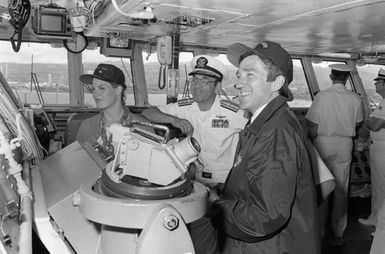 Secretary of the Navy John F. Lehman Jr., right, Mrs. Lehman, and RDML Lawrence C. Chambers visit the bridge of the aircraft carrier USS KITTY HAWK (CV-63)