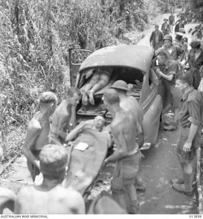 1942-12-16. PAPUA. GONA. WOUNDED AUSTRALIANS, PROBABLY FROM THE 55/53RD BATTALION, BEING PLACED IN A SEDAN CAR WHICH WAS CONVERTED INTO AN AMBULANCE. THIS CAR WAS CAPTURED BY THE JAPANESE AT ..