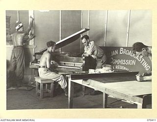 PORT MORESBY, PAPUA, NEW GUINEA, 1944-02-14. CARPENTERS AND A PIANO TUNER AT WORK IN STUDIO 2 IN PREPARATION FOR THE OPENING OF THE AUSTRALIAN BROADCASTING COMMISSION RADIO STATION 9PA. THE OFFICER ..