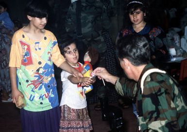 US Navy Photographer's Mate 2nd Class Cordell greets the first group of Kurdish children arriving on board Anderson Air Force Base, Guam, during evacuation of refugees from Northern Iraq. Operation PACIFIC HAVEN represents a series of airlifts designed to provide sanctuary for some 2,400 refugees fleeing Iraq. Many are considered traitors by the Iraqi Government for working with the CIA-funded Iraqi National Congress and international humanitarian agencies. The Kurds will be housed at Andersen AFB, while they go through the immigration process for residence in the United States